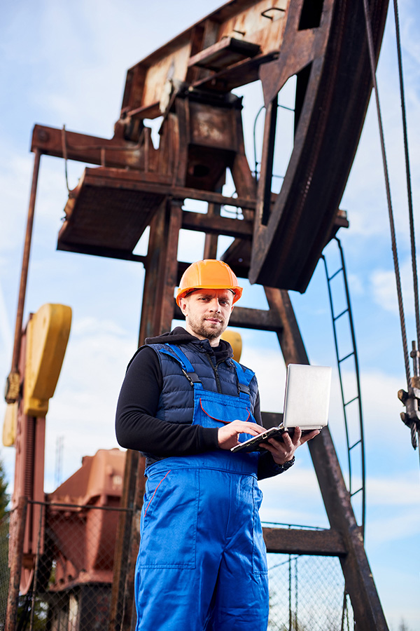 oil-engineer-with-a-laptop-standing-next-to-an-oil-DLZ7RBS.jpg