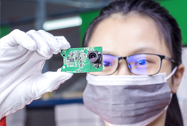 Technician inspecting PCB for camera system quality control